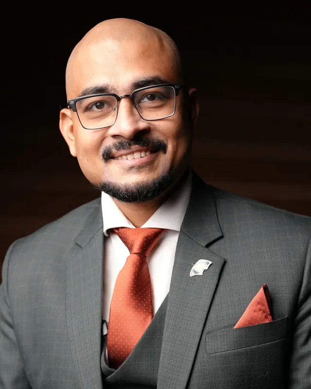 Sabbir Ahmed in a grey suit and terracotta tie